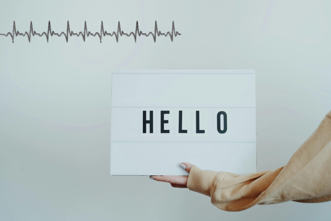 A hand holding a sign that says hello and there are heart beat pulses in the upper left corner