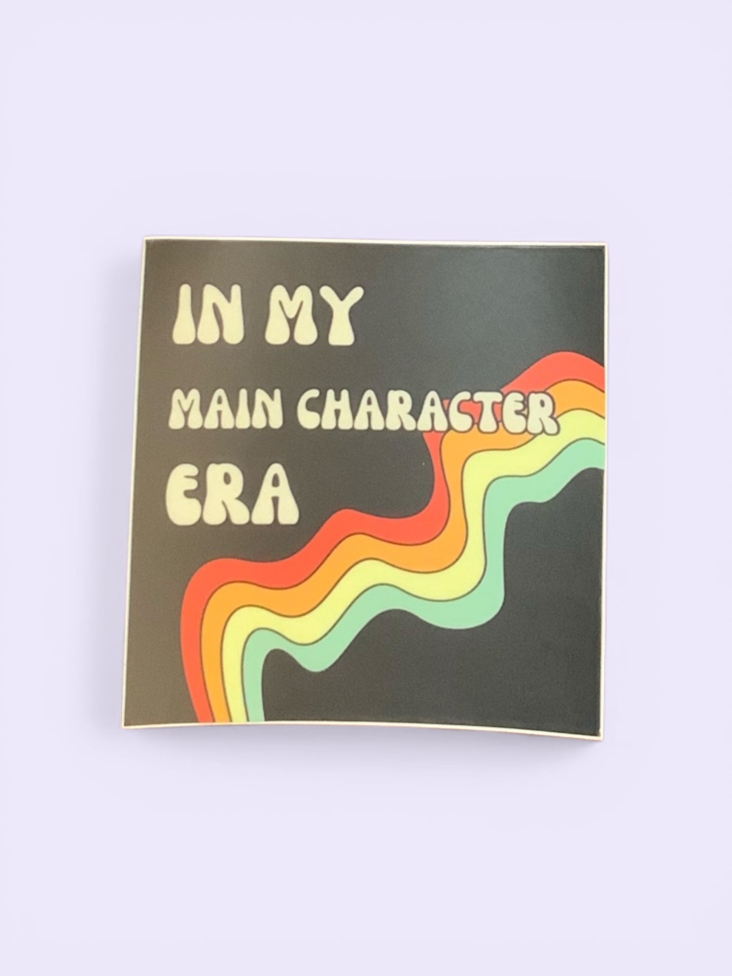 Sticker with text 'IN MY MAIN CHARACTER ERA' and colorful wavy design on a black background