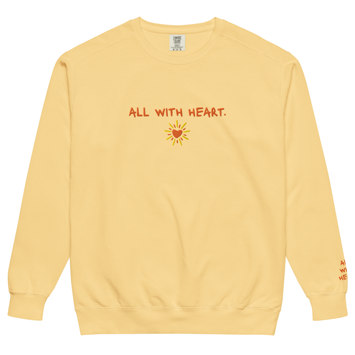 A yellow crewneck it’s a heart sun design that says “All With Heart” in orange embroidery.