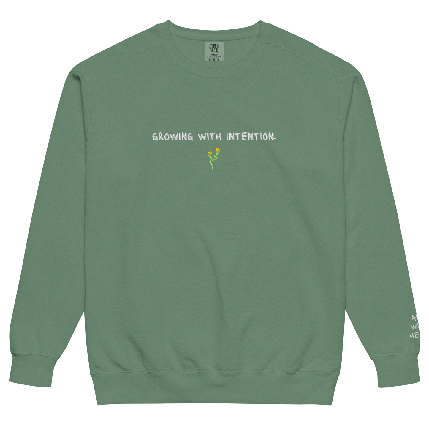 A green eco-conscious crewneck with “Growing With Intention” text and yellow flower design.