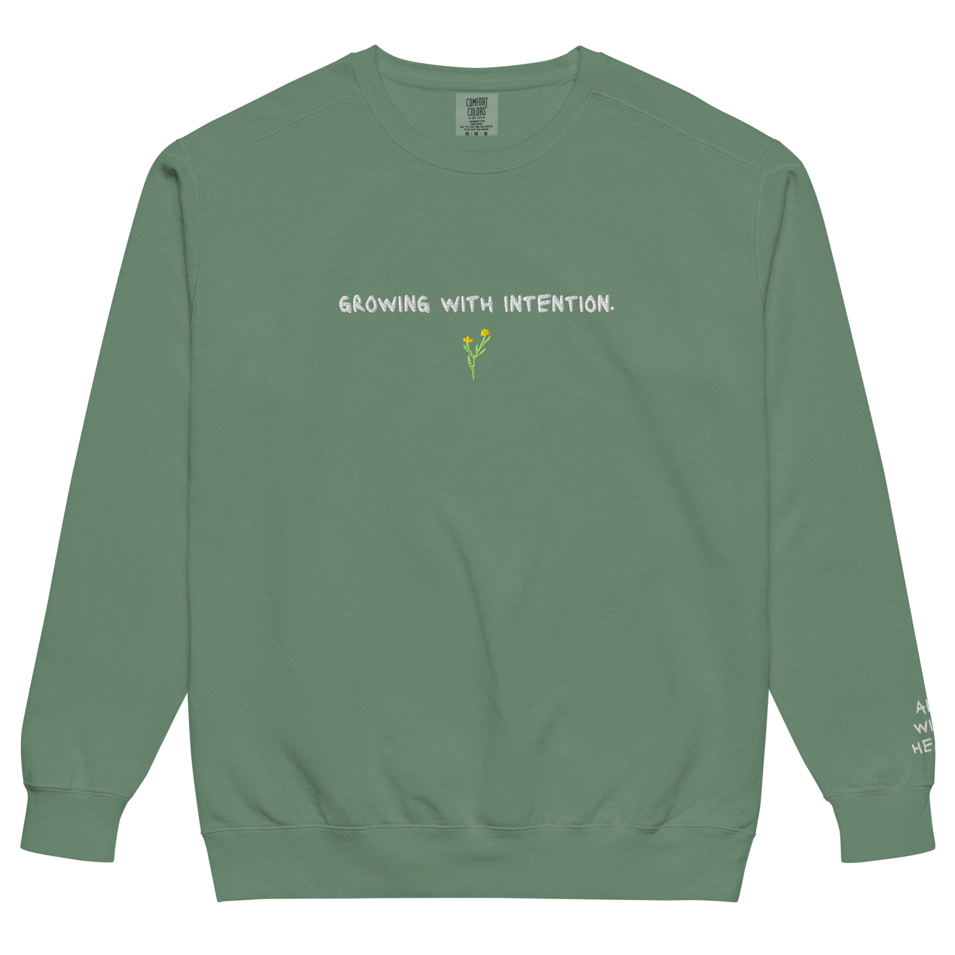 A green eco-conscious crewneck with “Growing With Intention” text and yellow flower design.