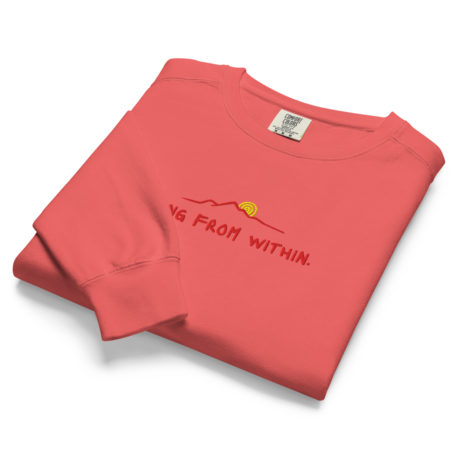 A folded bright red Crewneck that says “Rising From Within” with a mountain ridge design.